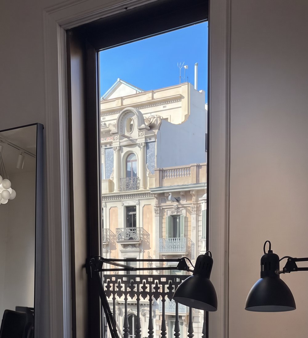Puesto de trabajo junto al balcón, con la fachada del Eixample al fondo